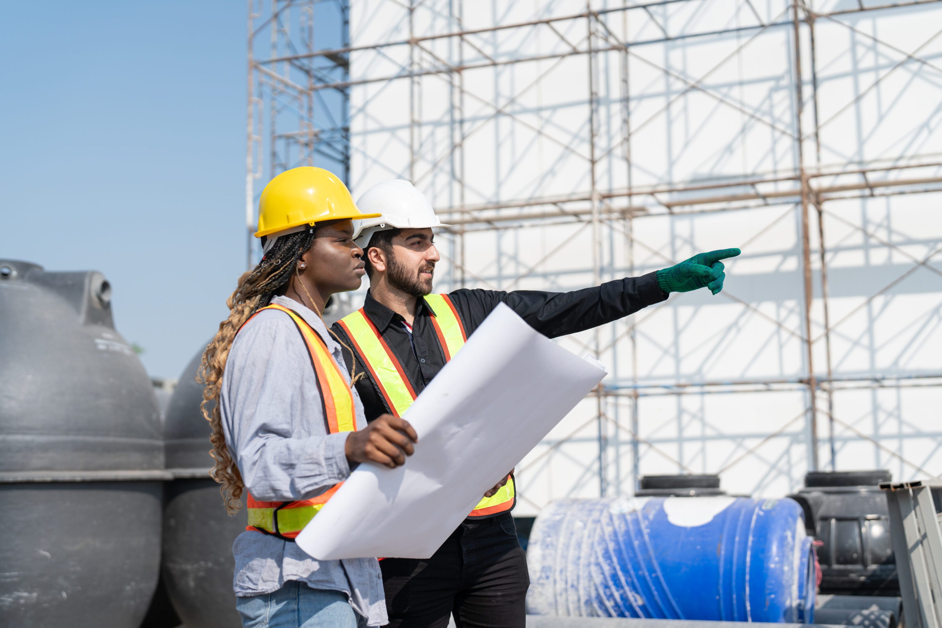Civil engineer and architect with blueprint discussing inspecting structure building project at construction site.